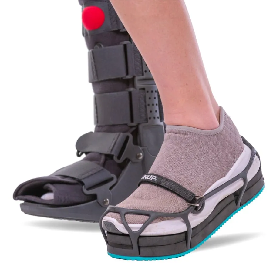 A cam boot on one foot and a sneaker strapped into an EvenUp on the other, bringing both to the same height