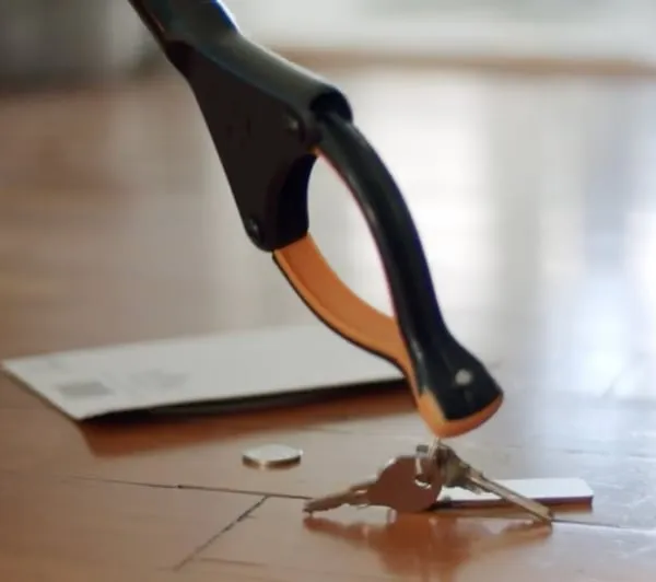 Grabber tool picking a set of keys up off a wood floor